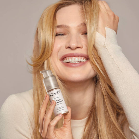 Woman holding a bottle of Kitsch product against a neutral background
