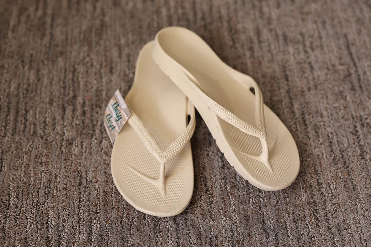 Pair of beige flip-flops on a textured brown surface