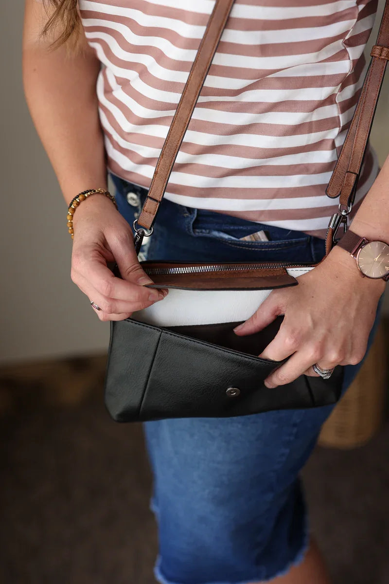 Person holding a black handbag with a striped shirt and blue jeans