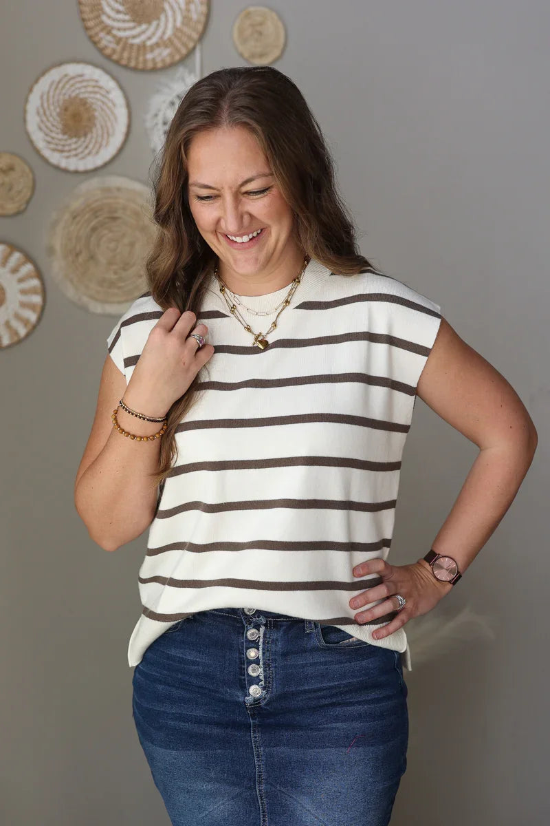 Woman wearing a striped shirt and blue jean skirt against a neutral background