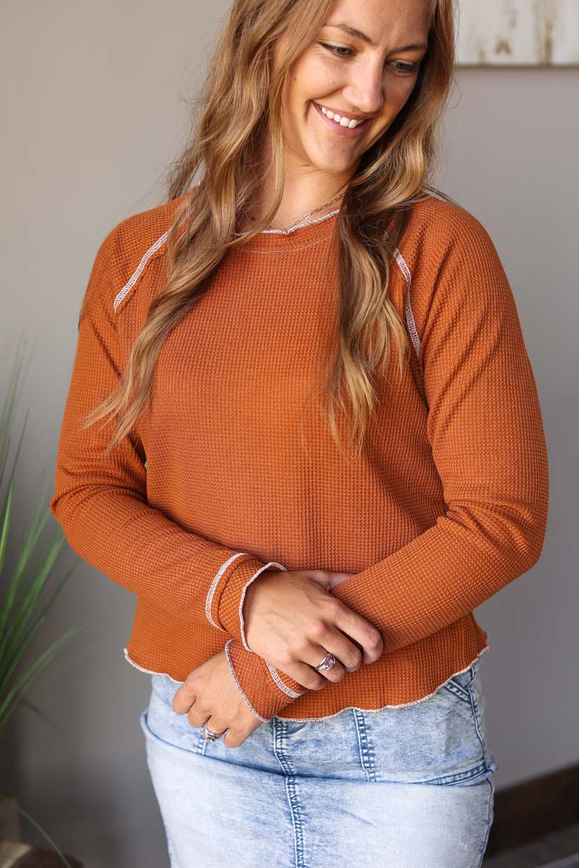 This Camel Textured Crewneck Long Sleeve Top is a chic fashion statement with a textured deep camel color. The feminine ivory hem line detail provides an elegant touch, plus the slightly shorter length makes it perfect for dressing up high rise styles.