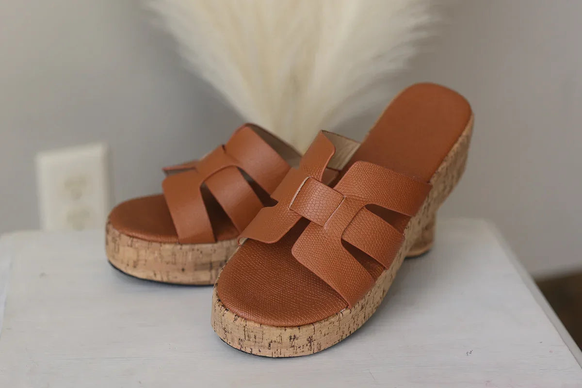 Brown sandals with cork platforms on a white surface with a blurred background