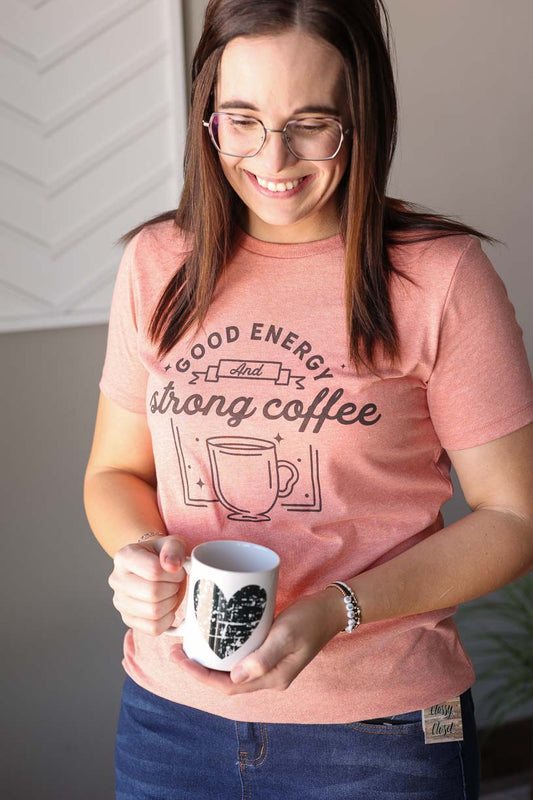 Start your day with a smile in our Heather Sunset "Good Energy Strong Coffee" Tee. As a mama, you know the importance of positive vibes, so why not style it with this slim-fit, graphic tee. Comfy and stylish, it's the perfect mantra for any mom on the go. 
We recommend sizing up as this is a slim-fit cut Bella Canvas tee. Classy Closet Hull Iowa online women's clothing boutique for modest fashion, cute mom outfits, spring summer 2025 trends. Cute, modest, affordable women's tops.
