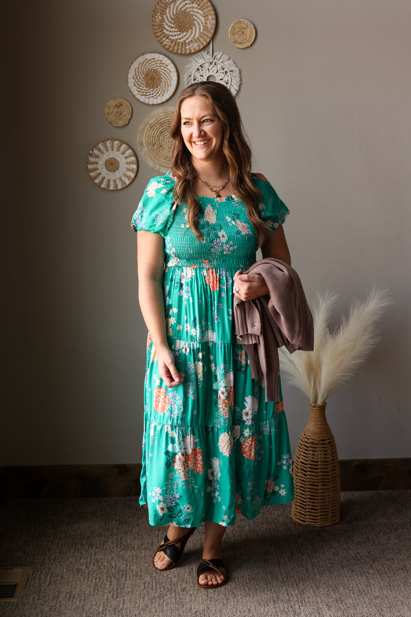 Woman in a floral dress standing in a room with decorative wall art.