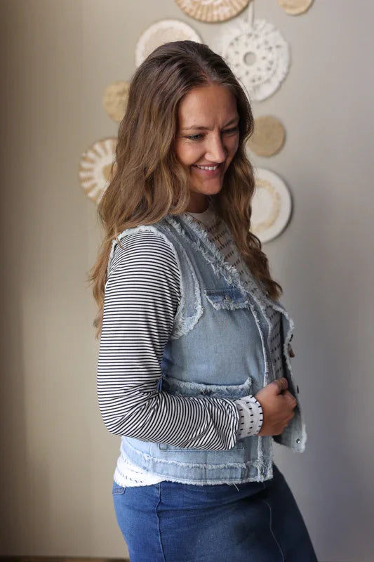 Women’s frayed denim vest jacket layered over a long sleeve top