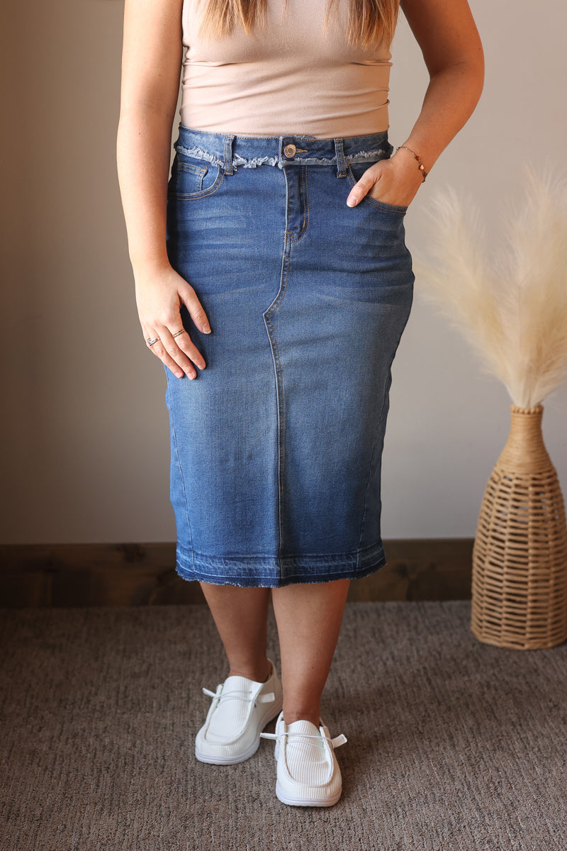 Person wearing a blue denim skirt with a neutral background