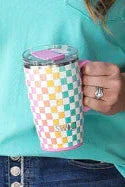 Woman in turquoise shirt and denim skirt holding a polka dot mug in a room with decorative wall art.
