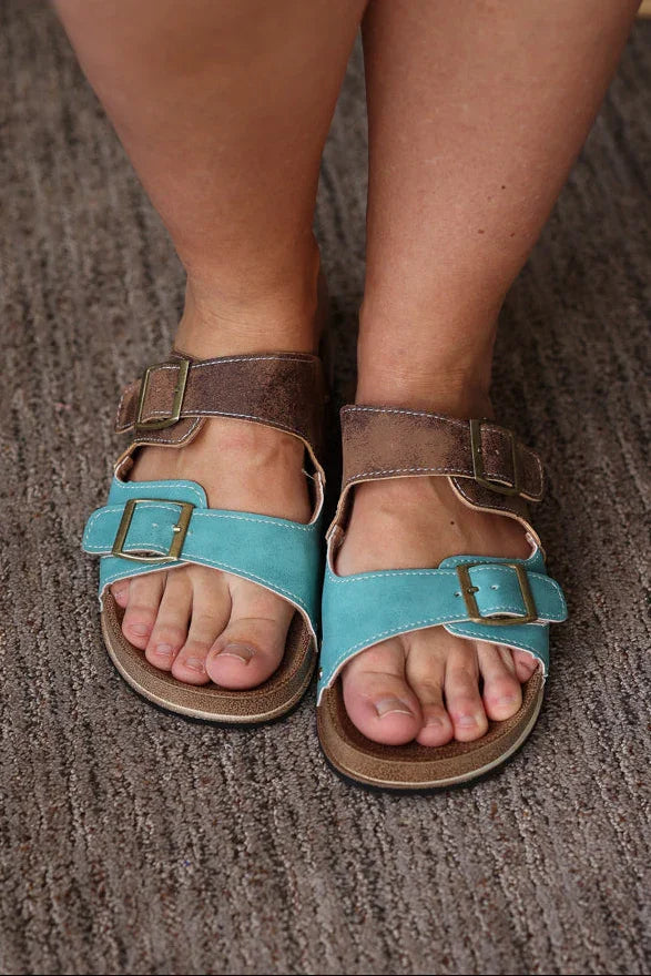 Person wearing blue sandals on a textured floor
