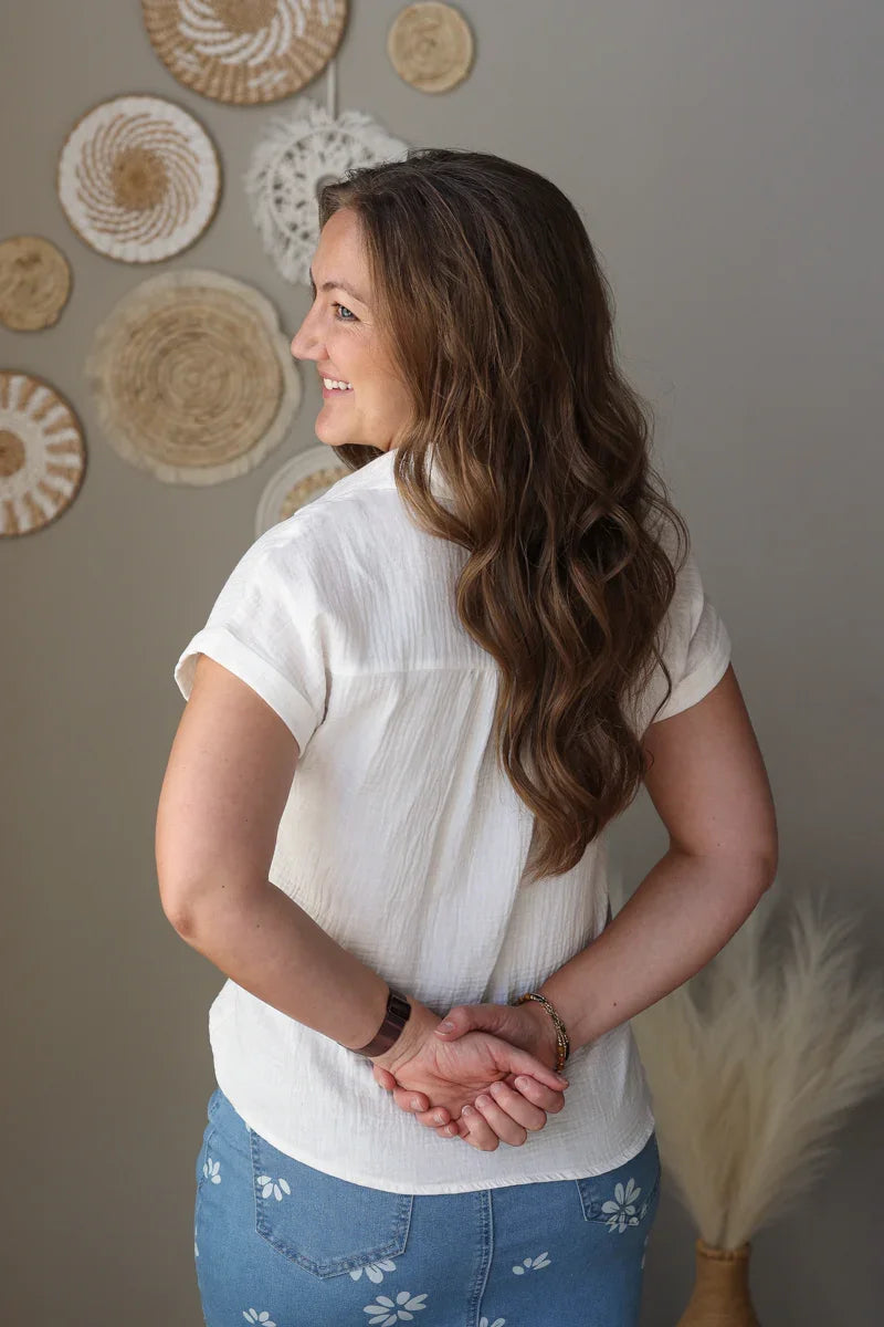 Woman in a white blouse and blue jean skirt standing in a room with decorative wall art.