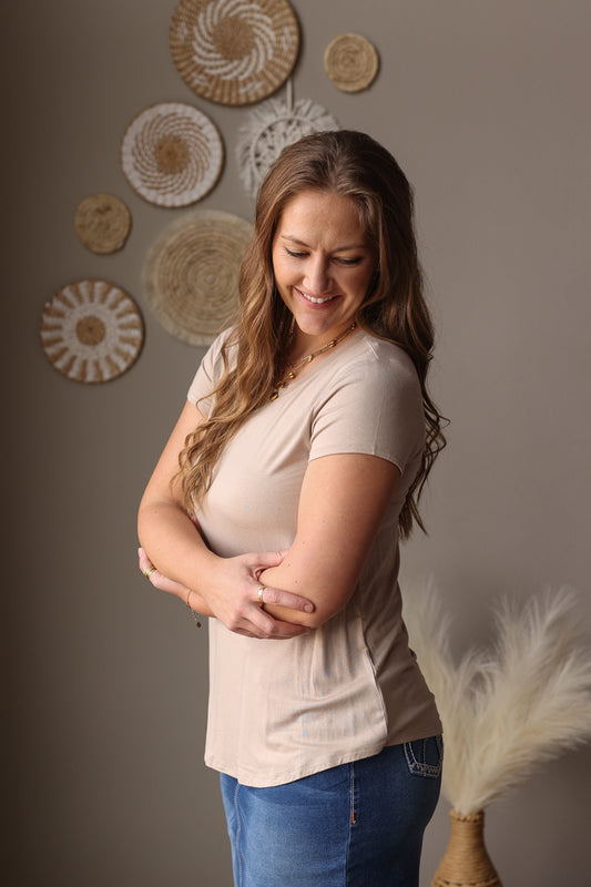 Woman standing with arms crossed against a wall with decorative plates.