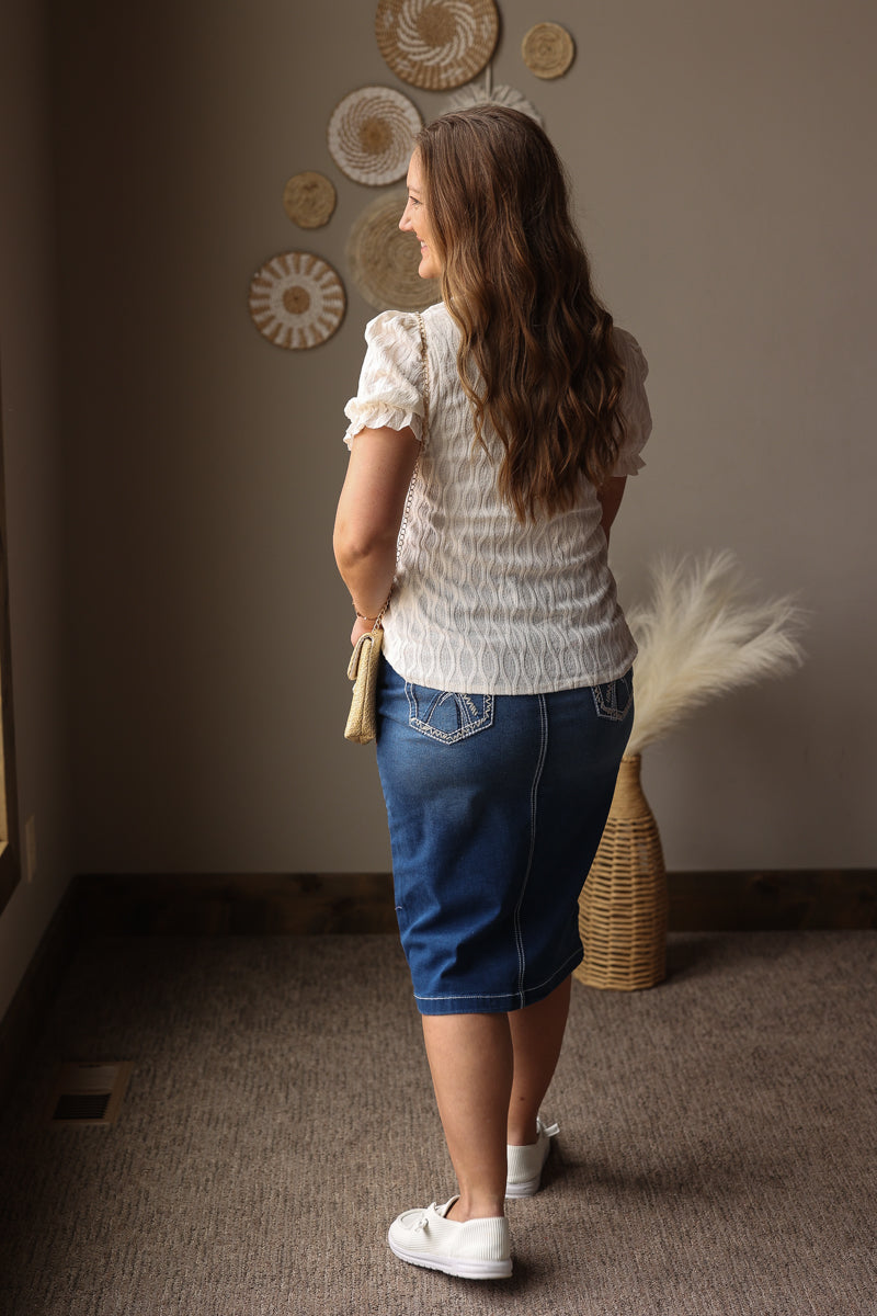 Woman standing in a room with decorative plates on the wall and a basket on the floor.