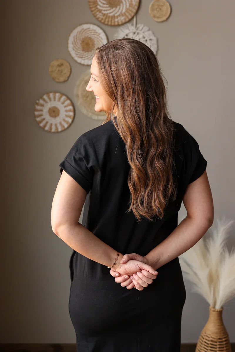 Woman in a black outfit standing in a room with decorative wall art.