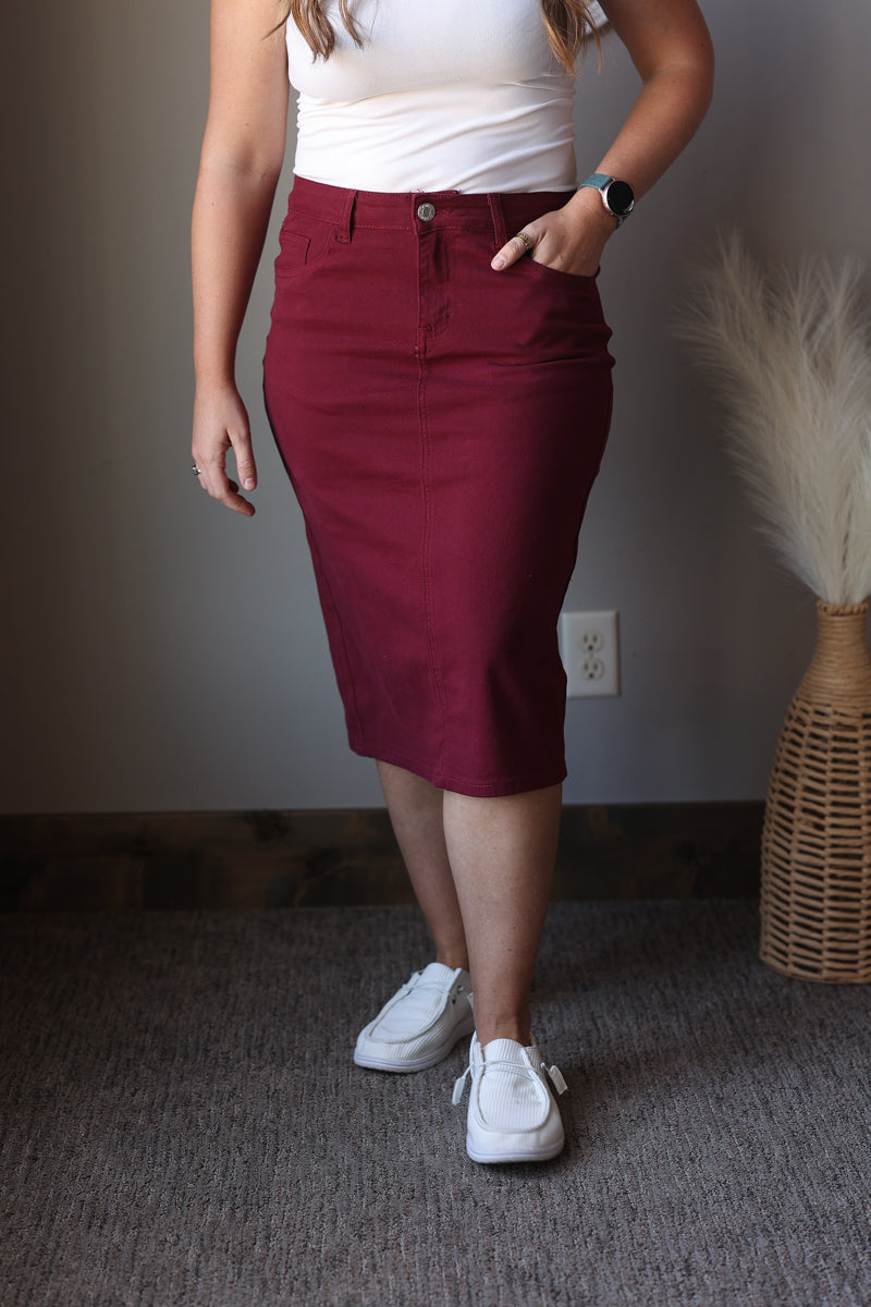 Person wearing a red skirt and white top indoors with a neutral background