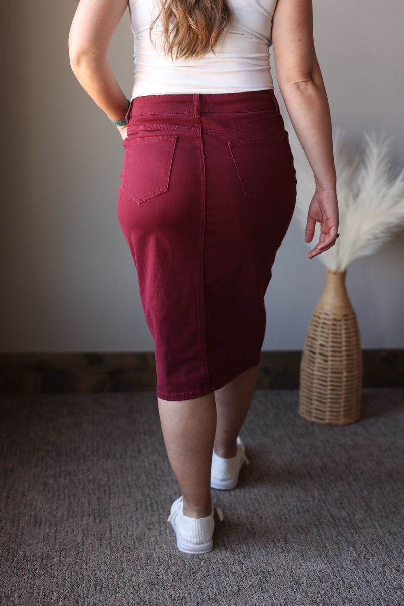 Person wearing a maroon skirt with a plain background