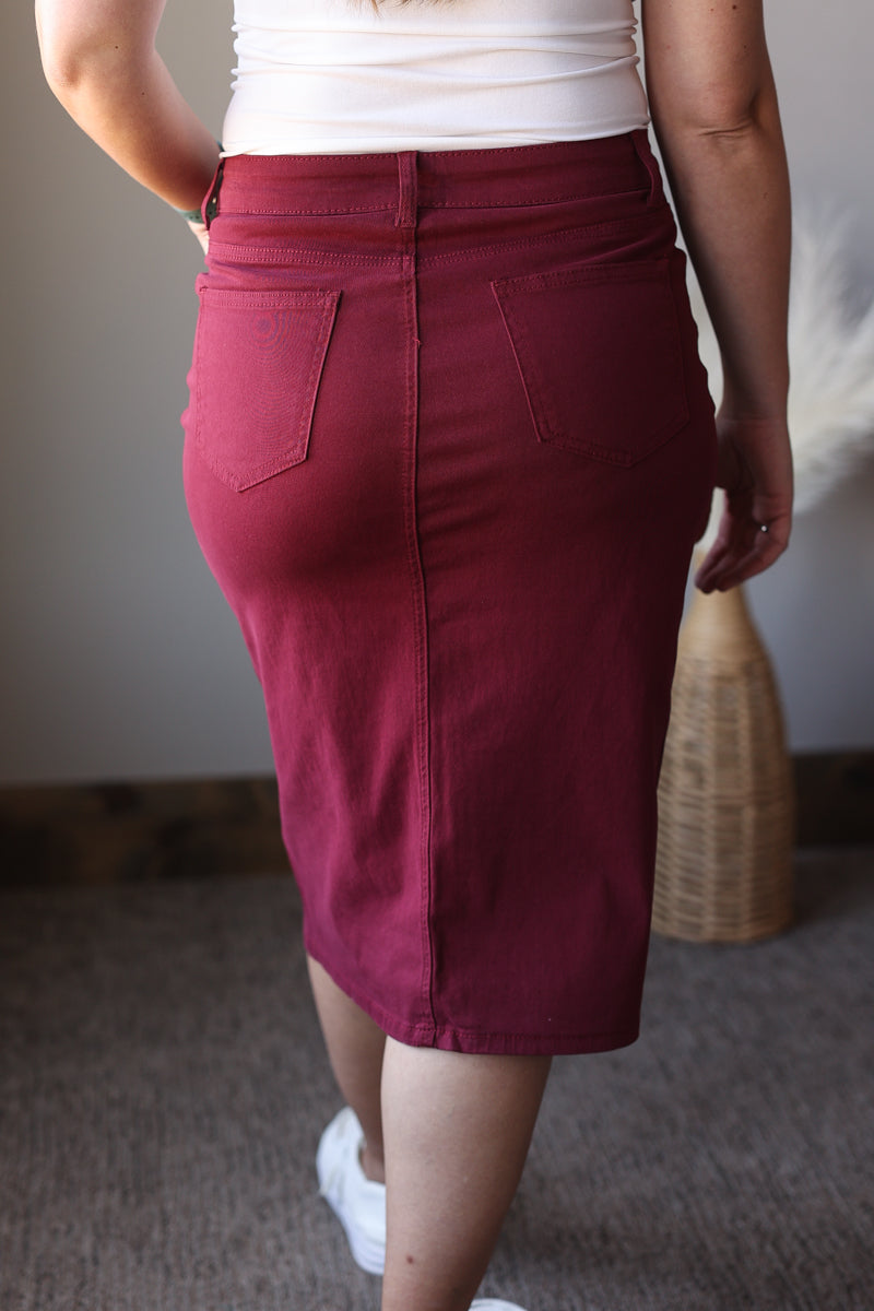 Person wearing a maroon skirt with a neutral background