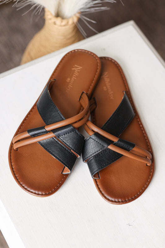 Pair of brown and black sandals on a white surface