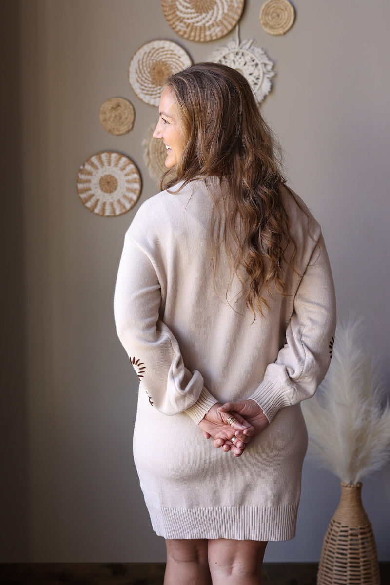 Back view of a parchment long sleeve sweater dress showing the plain knit back and ribbed hem.