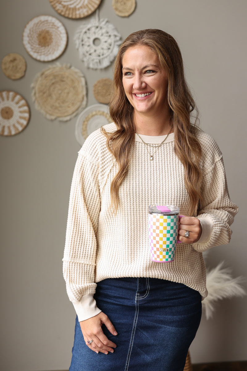 cream waffle long sleeve very j top with a dark wash denim skirt and holding the checkmate swig tumbler.