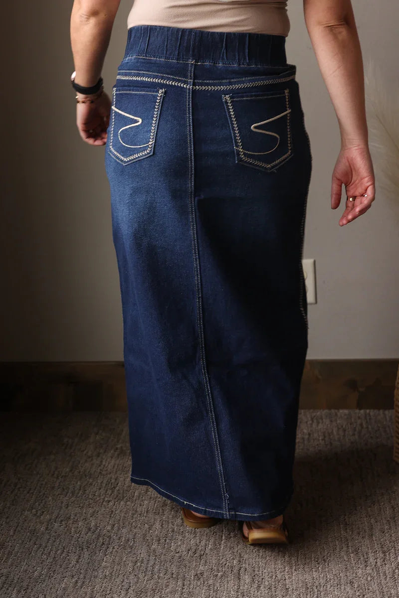 Person wearing a long blue denim skirt indoors.