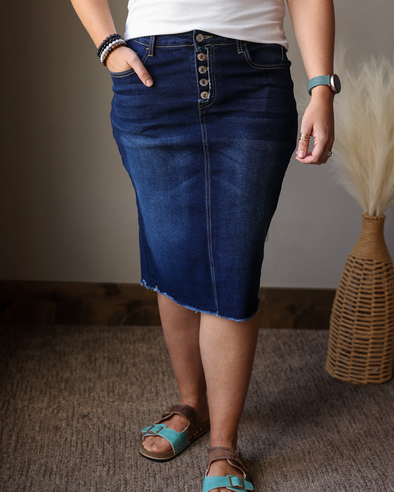 Person wearing a blue denim skirt with a plain background