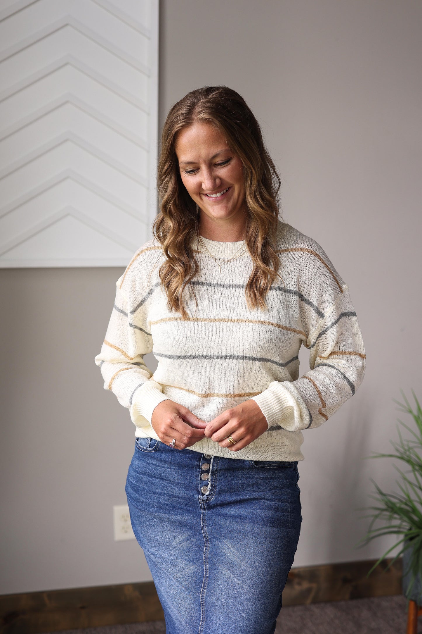 Woman wearing a striped sweater and blue jean denim skirt for modest fall outfits.