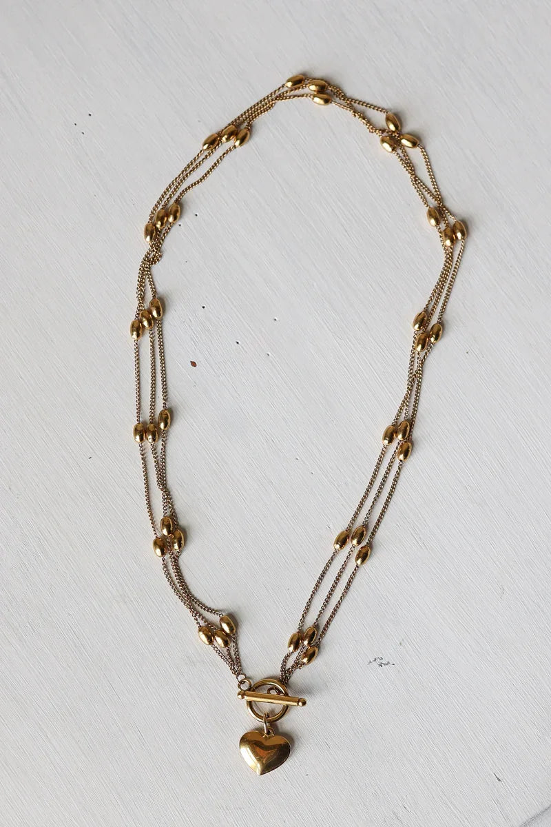 Gold necklace with heart-shaped pendant on a white background