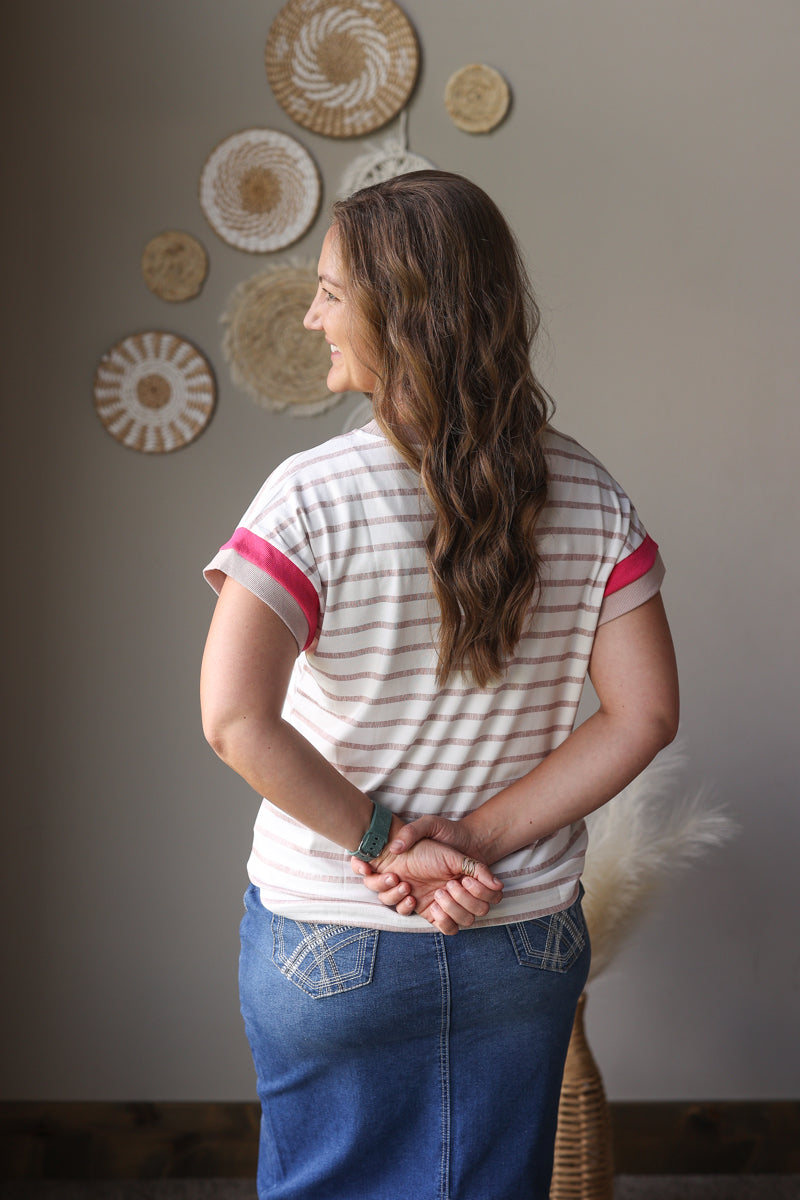 Woman standing with hands clasped in front of a wall with decorative plates.