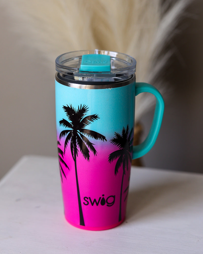 SWIG 22oz Turquoise and pink mug with palm tree design and 'swig' branding on a white surface.