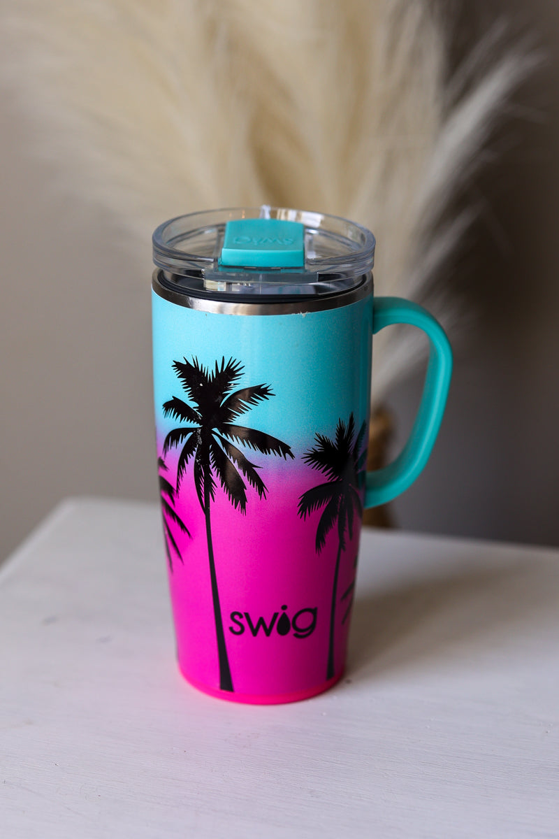 SWIG 22oz Turquoise and pink mug with palm tree design and 'swig' branding on a white surface.
