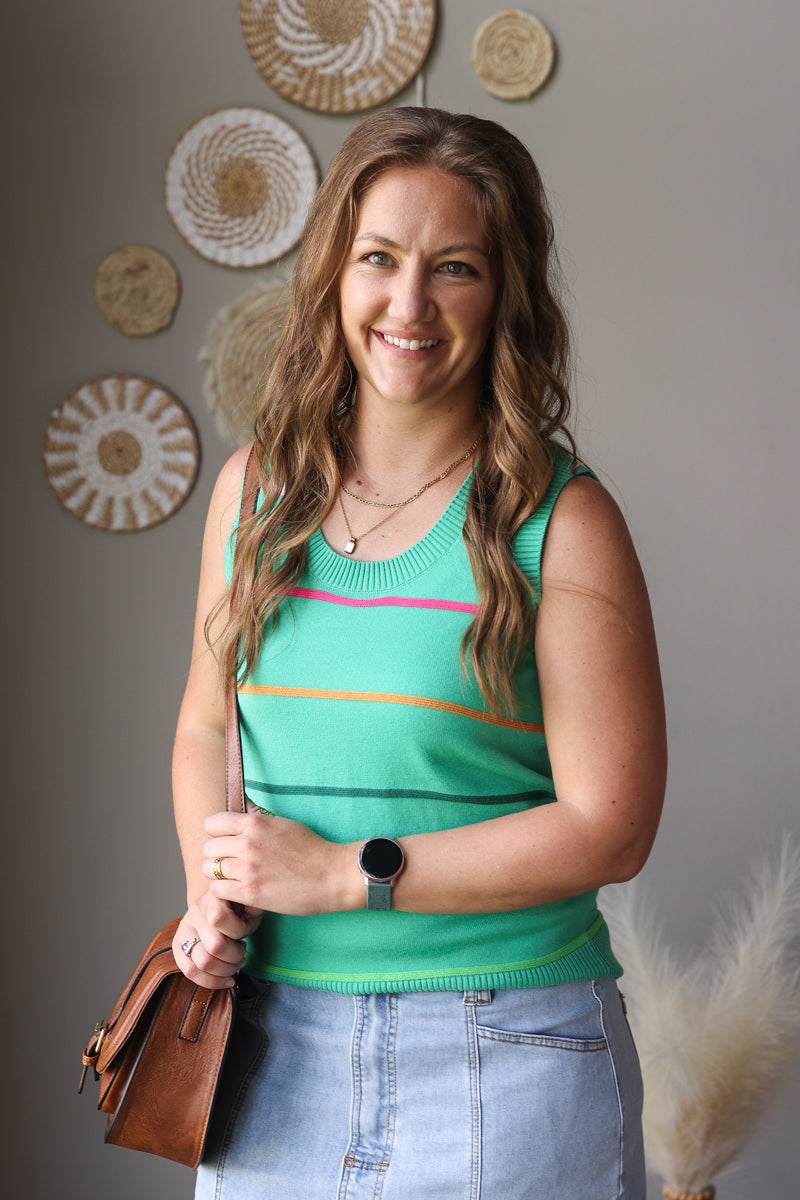 Woman wearing a green tank top with decorative plates on the wall behind her