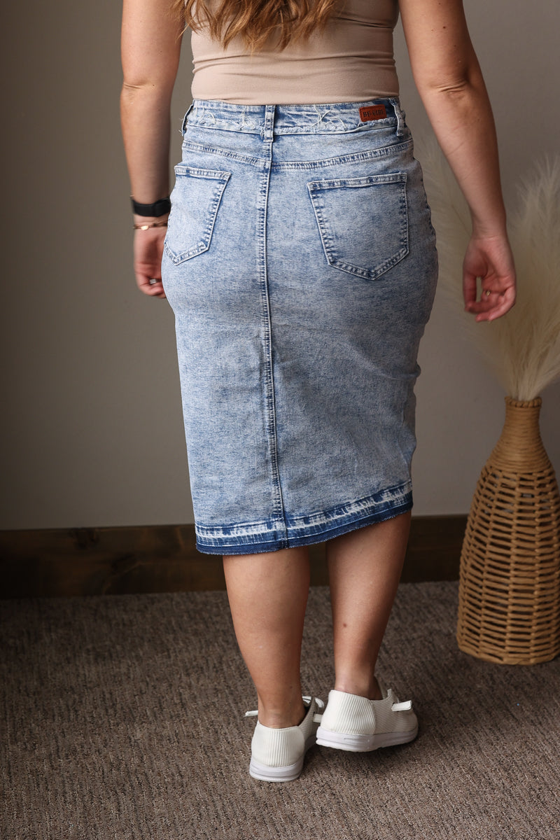 Person wearing a denim skirt with a neutral background