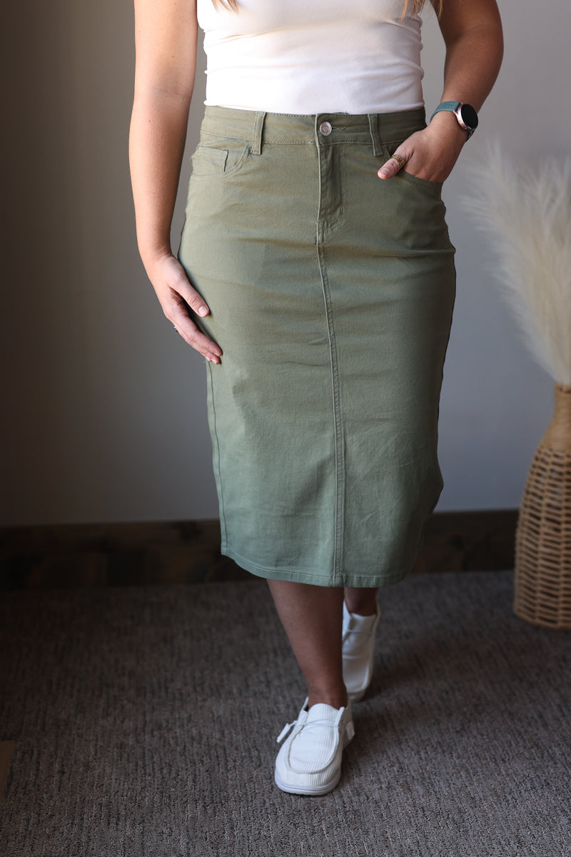 Person wearing a green skirt and white sneakers in an indoor setting