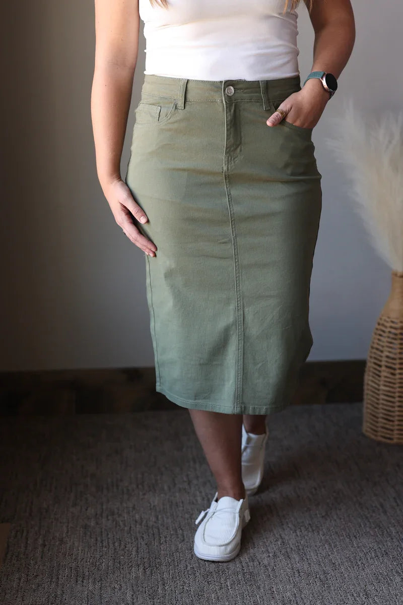 Person wearing a green skirt and white sneakers in an indoor setting