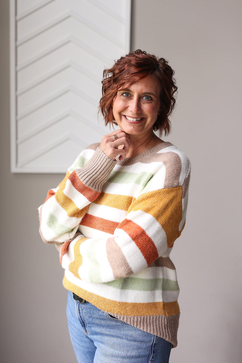 Woman wearing a colorful striped sweater against a neutral background