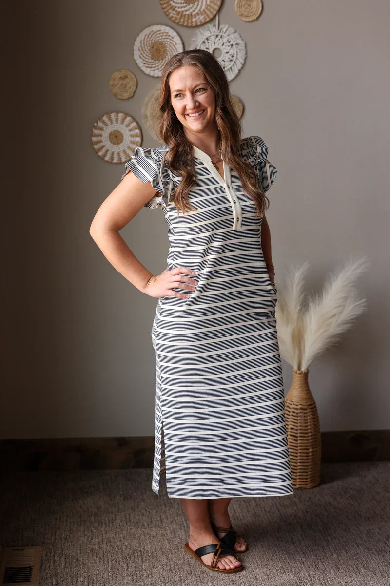 Woman wearing a striped dress standing in a room with decorative wall art.