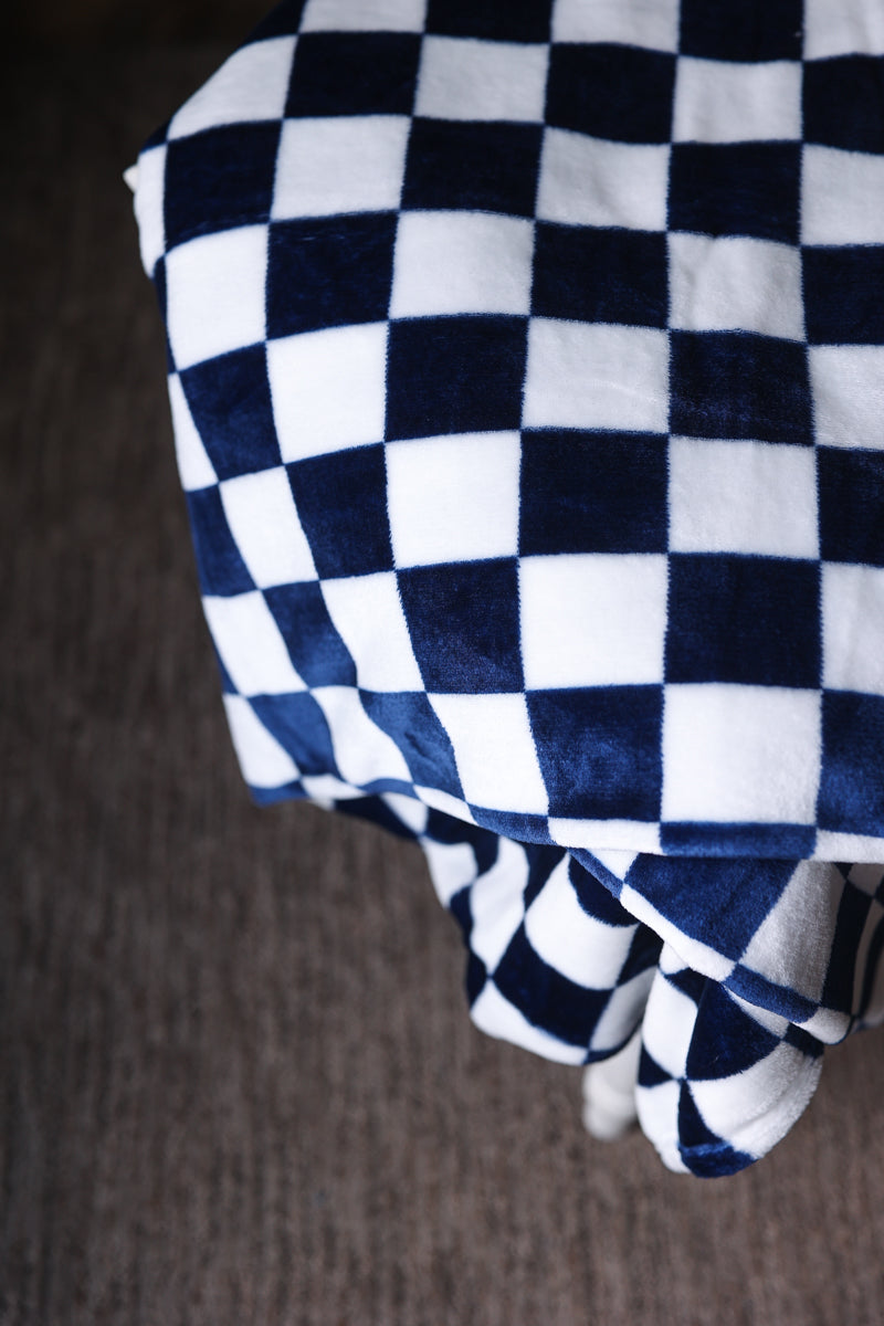 Folded checkered blanket with blue and white pattern on a brown surface