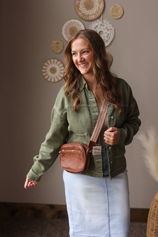 Woman wearing a smoke green denim jacket with brown crossbody purse and light wash denim skirt for a cute, chic, fall winter outfit.