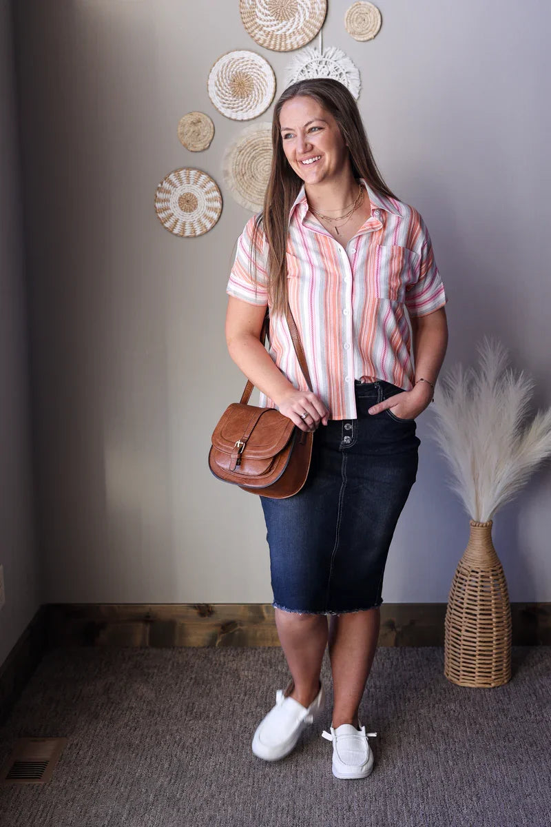 Woman holding a brown handbag indoors with decorative wall art in the background