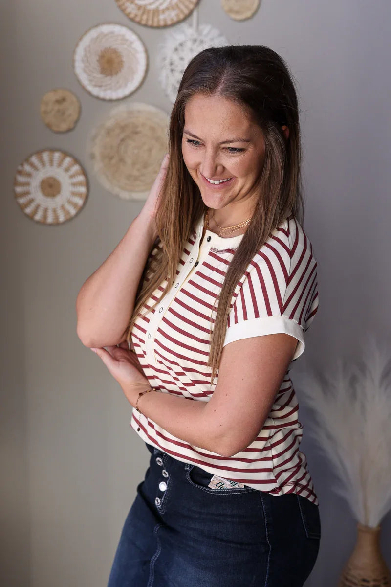 Woman wearing a striped shirt standing against a wall with decorative plates.