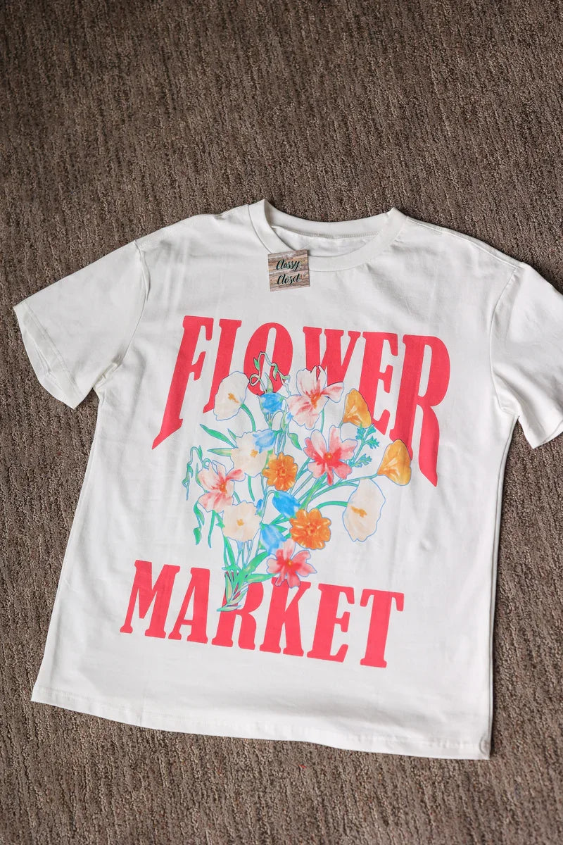 White t-shirt with 'Flower Market' graphic on a brown surface