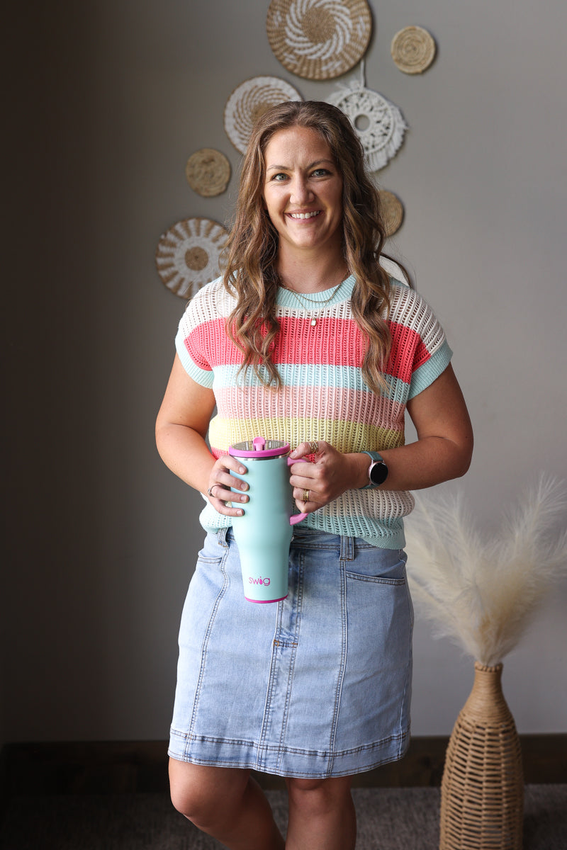 Woman holding a tumbler in a room with decorative wall art