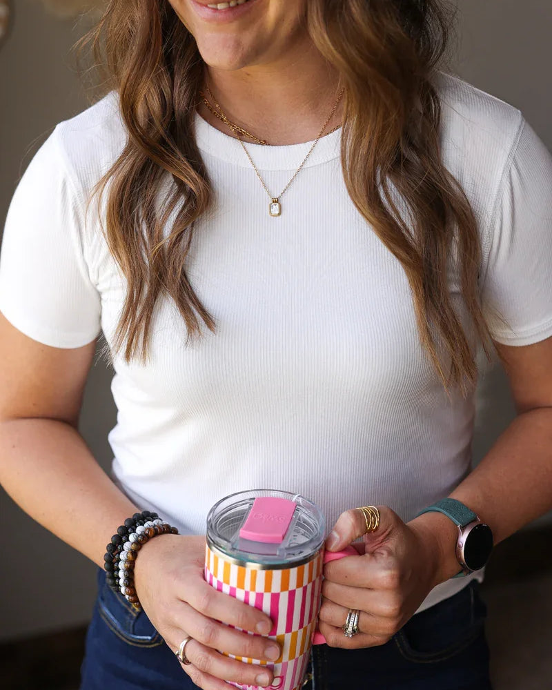 Woman holding a striped tumbler with a pink lid indoors