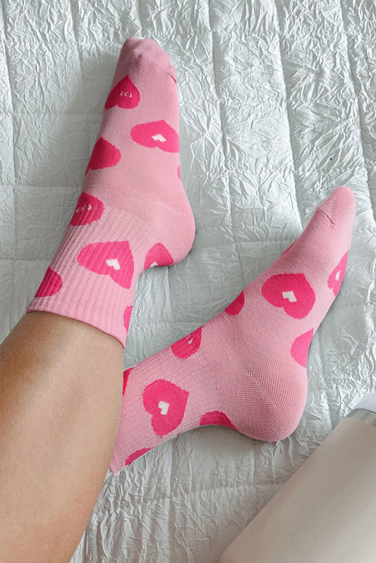 Pink socks with heart patterns on a textured white surface