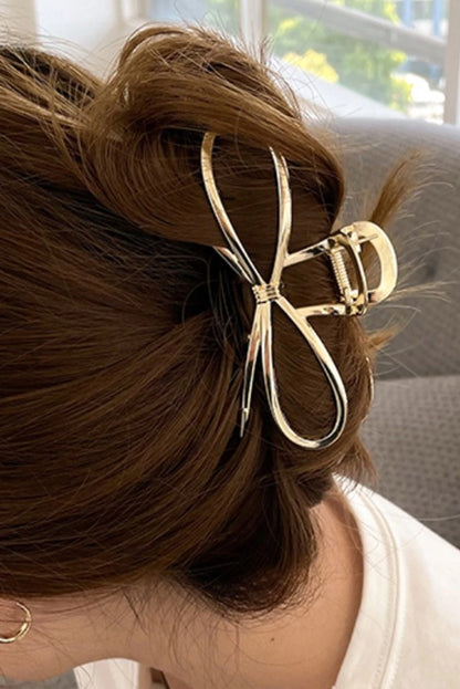 Hair clip with bow detail in a person's hair, with a blurred indoor background