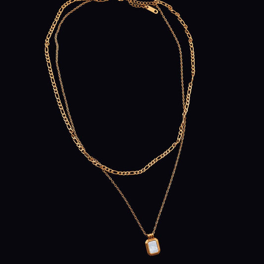 Gold chain necklace with a pendant on a black background