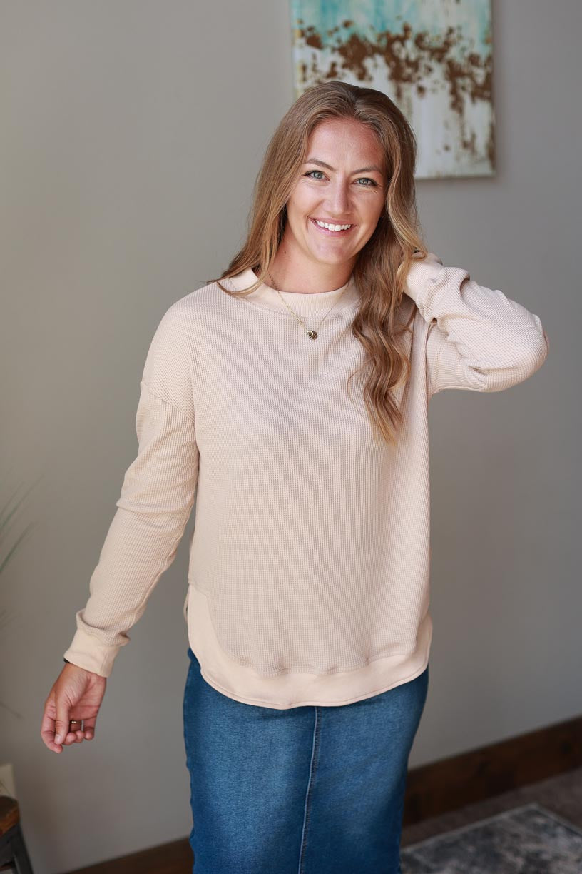 This beige crewneck top is the perfect blend of comfort and style. Its cozy, waffle sweatshirt-like feel is conveniently fashionable, and side slits add a chic finish. This top is ideal for those looking for an effortless yet sophisticated work style.