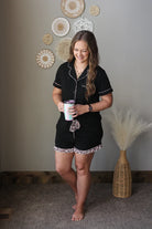 woman wearing a black 2 piece button up shorts pajama lounge set with animal leopard trim contrast