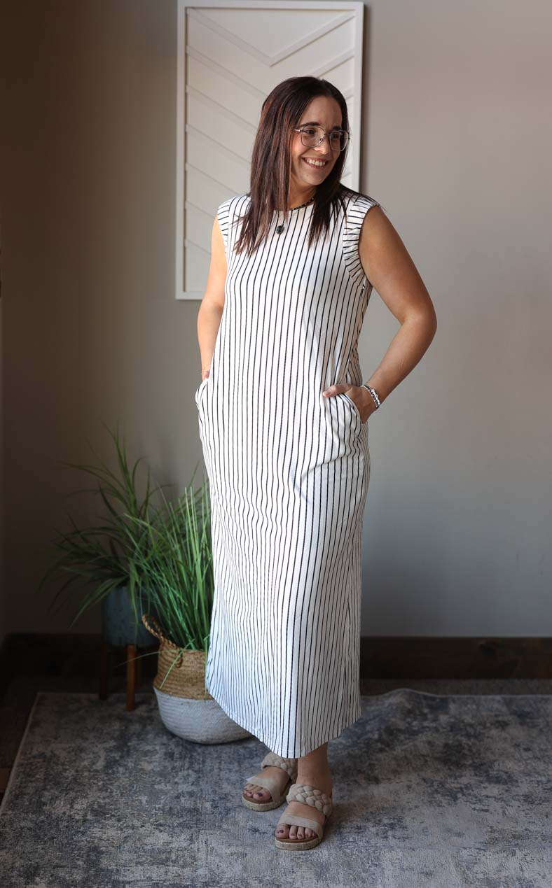 Embrace the versatility of this flattering Black White Stripe Sleeveless Maxi Dress. The vertical stripes create a stylish and slimming look, while the addition of pockets and a crewneck make it a practical and comfortable choice. Perfect for all year round, this dress is a must-have in your wardrobe. Classy Closet online women's clothing store with modest fashion and trendy affordable tops. Hull iowa