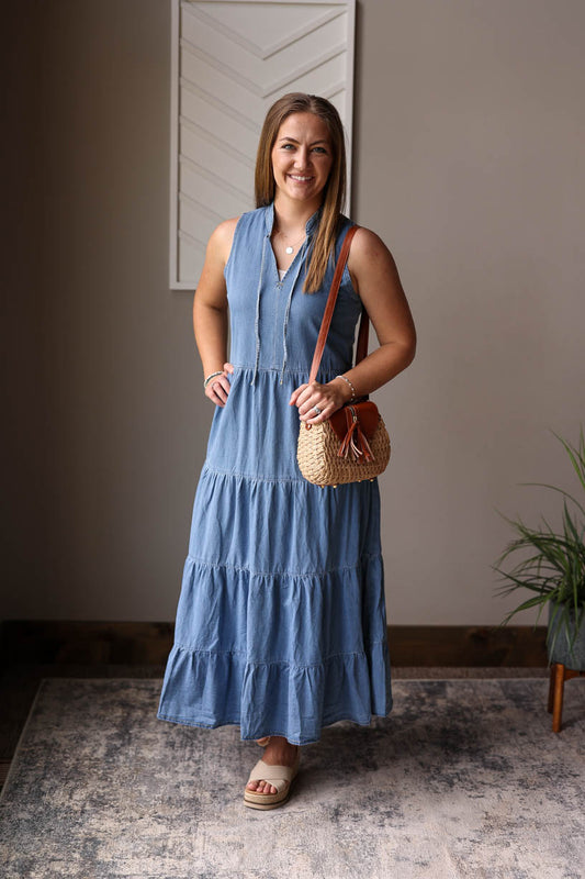 Effortlessly chic and perfect for summertime, our Blue Chambray Sleeveless Tiered Maxi Dress is a must-have for any wardrobe. This dress features a v-neckline, slight mock collar, and tiered design for a casual yet polished look. Made from soft denim, it's comfortable and stylish for any occasion. Classy Closet modest summer dresses for women