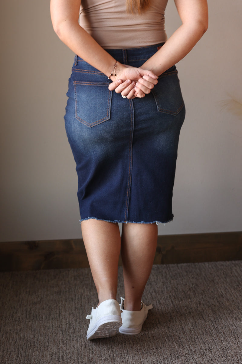 Person wearing a blue denim skirt with a neutral background